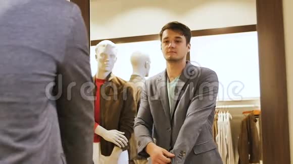 男人穿灰色夹克在商场里镜子里看视频的预览图