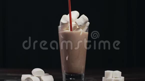 在玻璃杯中加入饮料管加入热可可饮料和棉花糖用牛奶制成可可喝热的视频的预览图