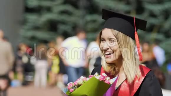 快乐美丽的毕业学生捧着一束鲜花微笑着对着镜头视频的预览图