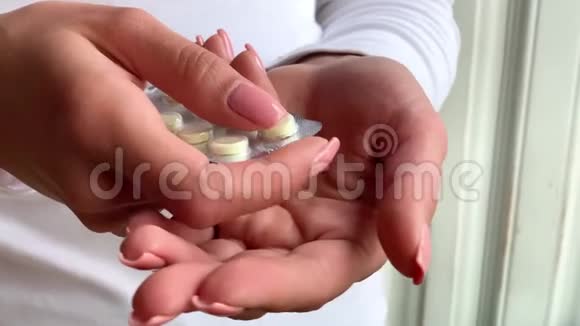 女人手从水泡包里拿药丸特写女性手倒白圆片手中的药物剂量药丸视频的预览图