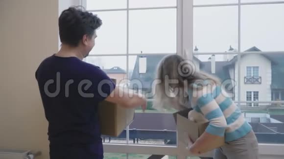双手拿着盒子的成年男女在新房子的窗户里看着视频的预览图