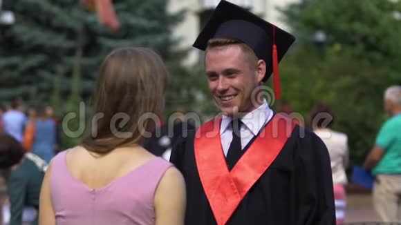 快乐的男毕业生微笑着把他的学术帽戴在小妹妹身上视频的预览图