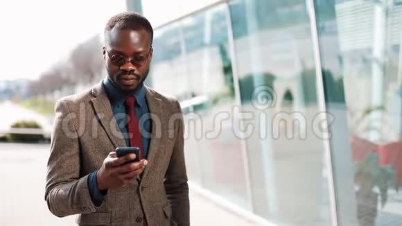 非裔美国商人站在办公中心附近用智能手机说话商务人员交流视频的预览图
