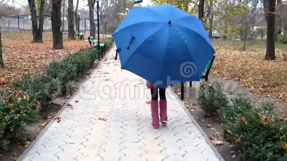 女孩子在蓝色的伞下行走视频的预览图