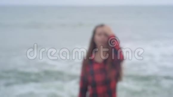 阴天时年轻漂亮的欧洲女孩穿着格子衬衫在沙滩上沿着大海散步女孩视频的预览图