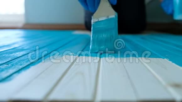 画家用他的画笔沿着一块木板用蓝色的颜料缓慢移动俯视视频的预览图