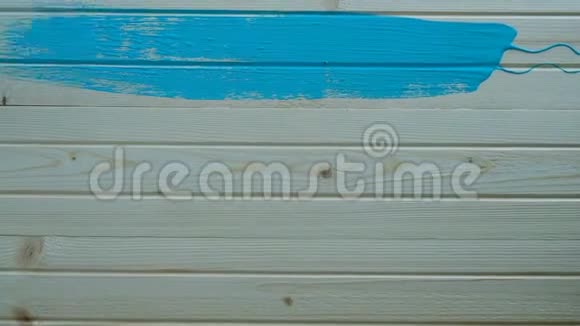 戴着蓝手套的油漆工慢慢地用绿松石油漆在木板上刷刷视频的预览图