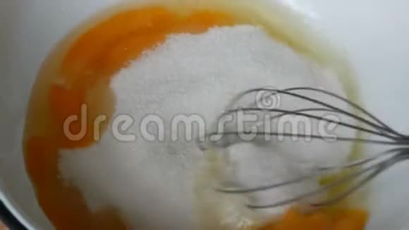 厨房用金属搅拌器将蛋黄蛋清和糖打在靠近视野的碗中视频的预览图