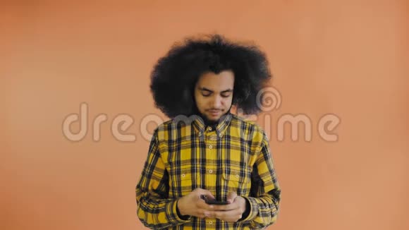 年轻英俊的非裔美国人在橙色背景下使用电话情感概念视频的预览图
