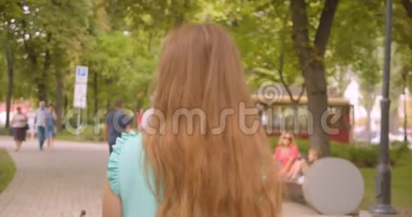 特写后景照片年轻的长发美女在公园户外散步视频的预览图