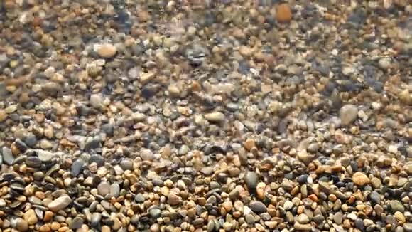 沙滩上的卵石被水冲洗特写海水卵石的质地视频的预览图