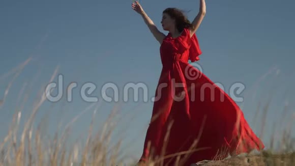 穿着猩红衣服的年轻女模特穿着风装赤脚摆姿势视频的预览图