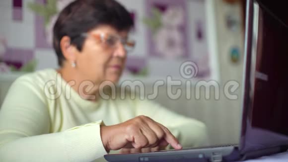 戴眼镜的老年妇女在家里用笔记本电脑上网有免费空间和复印空间视频的预览图