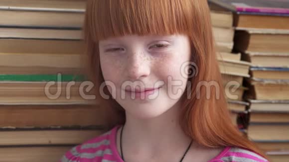 一个快乐的小女孩在书的背景上微笑的特写镜头视频的预览图