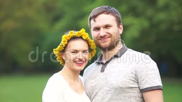 年轻的情侣在公园里散步封闭夫妻画像头上戴着花环视频的预览图