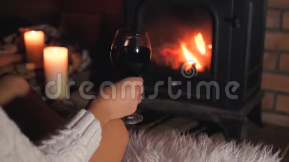 孤独的女人坐在壁炉前喝着酒杯里的酒视频的预览图