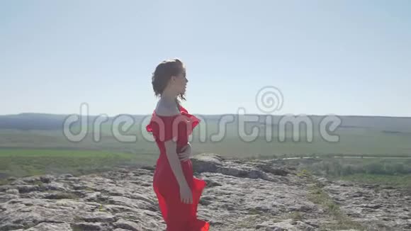 穿着猩红衣服的年轻女子随风飘舞望着远方视频的预览图