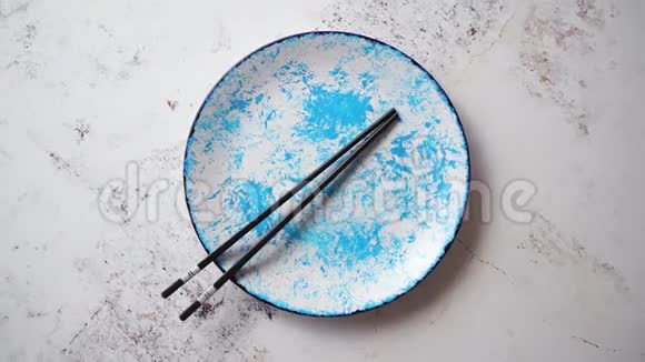 蓝色手绘陶瓷餐盘侧面有木制筷子视频的预览图