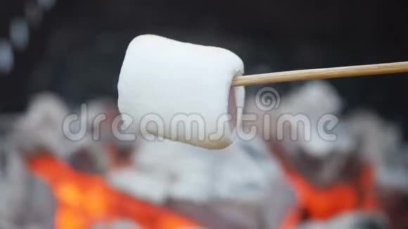 男人在户外的煤上炸棉花糖肉串上的棉花糖在木桩上炸了在热炭上烤棉花糖视频的预览图