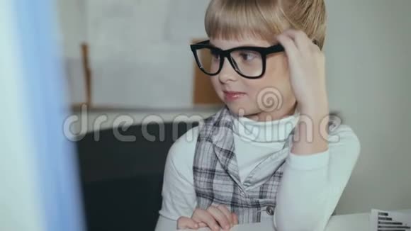 可爱的小女孩微笑的戴着眼镜心甘情愿地与电脑在办公室工作4K视频的预览图