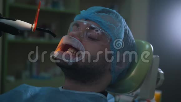医生和病人在牙科办公室用扩唇器用紫外线和橙色清洗和消毒视频的预览图