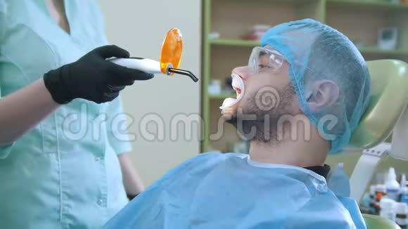 牙科办公室的医生和病人用橙色保护屏幕聚合填充物视频的预览图