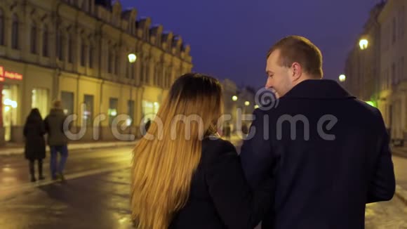 年轻夫妇走在城市灯火辉煌的夜晚街道上视频的预览图