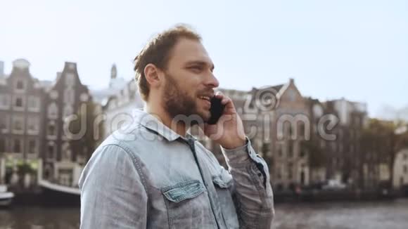 快乐的欧洲男人骑自行车在电话里说话4在码头古镇与朋友交谈的一个成年胡须男视频的预览图