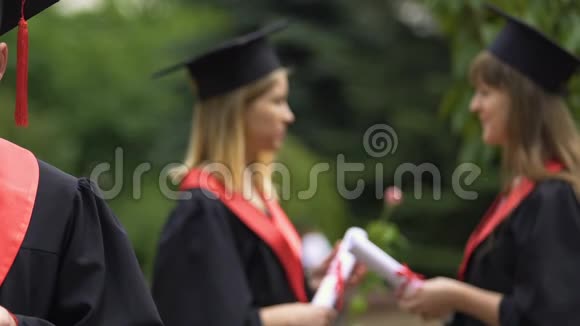 注意力不集中的女毕业生穿着学术服装说话手里拿着文凭视频的预览图