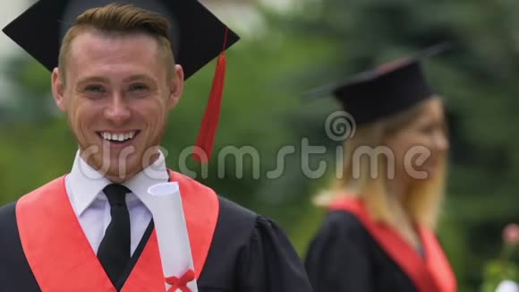 男毕业生穿着大学文凭微笑着拍照视频的预览图