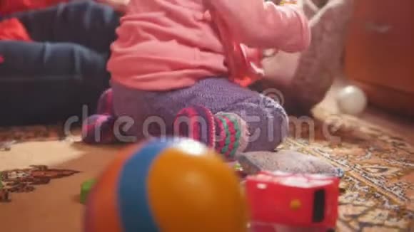 小女孩和她的祖母一起玩五颜六色的玩具坐在地板上专注于球视频的预览图