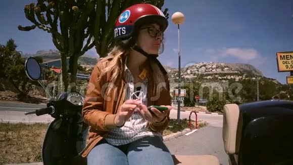 年轻的摩托车女司机在电话里聊天视频的预览图