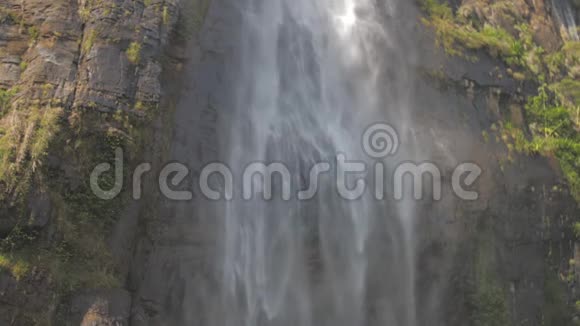 新鲜的水从高高的棕色岩石悬崖落下阳光照射视频的预览图