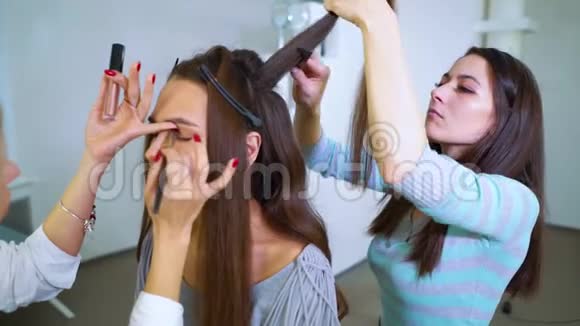 为漂亮的年轻女性化妆和发型的美容院女孩团队合作视频的预览图