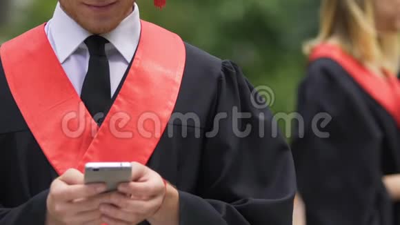 男性毕业生在智能手机上输入信息和浏览网页交流视频的预览图