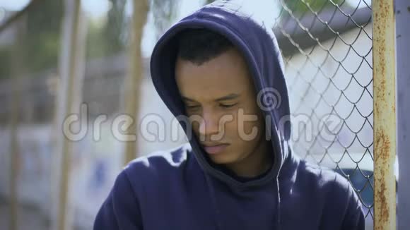 坐在栅栏旁的流氓男孩与家人失散的移民儿童被拘留视频的预览图