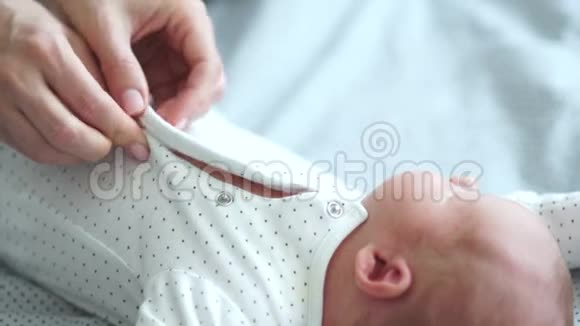 妈妈给她的新生婴儿穿上衣服轻轻地吻他母亲照顾母亲和婴儿视频的预览图