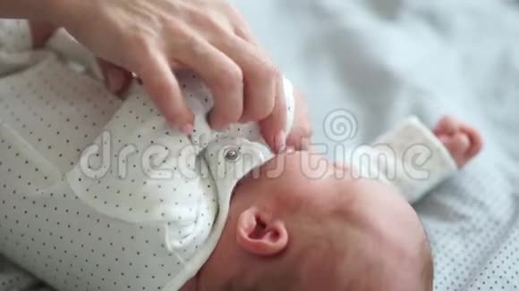 一位年轻的母亲给她新生的婴儿脱衣服轻轻地吻他母亲照顾母亲和婴儿视频的预览图