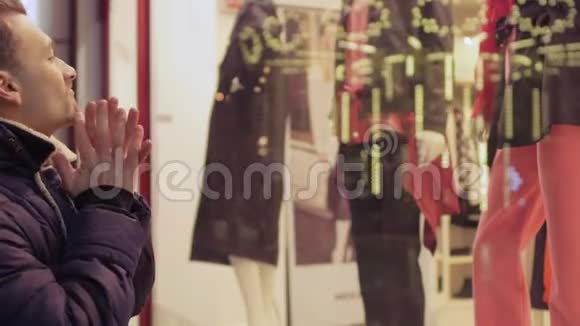 年轻人为妻子在商店橱窗里挑选衣服视频的预览图