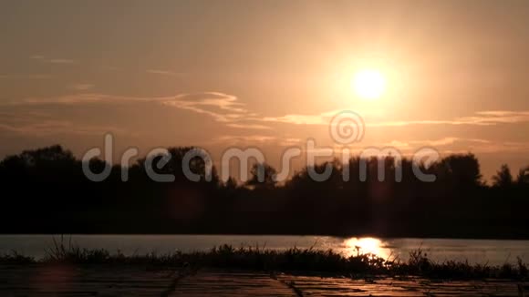 一个人在黎明时沿着堤岸骑着陀螺或赛格威的腿的特写日出或日落时剪影视频的预览图