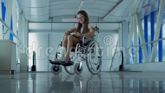 一个坐轮椅的年轻女孩正在看书医院走廊里坐轮椅的病人视频的预览图