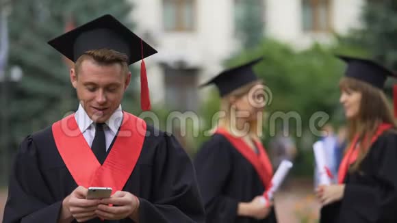 男毕业生在仪式前在智能手机上阅读好消息惊讶视频的预览图