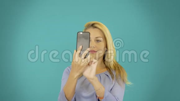 年轻女性在智能手机上自拍可爱的金发女孩制作手机相机复制空间视频的预览图