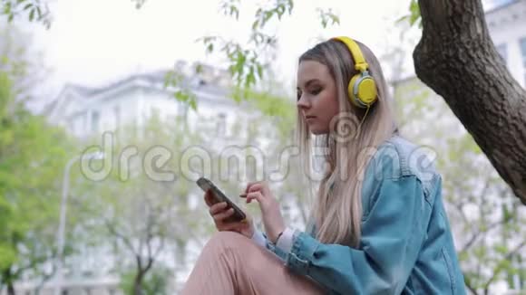 女人坐在公园的一棵树上听音乐视频的预览图