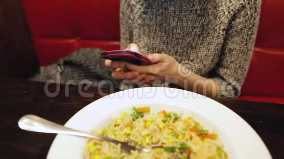 漂亮的女人用智能手机在咖啡馆里吃饭视频的预览图