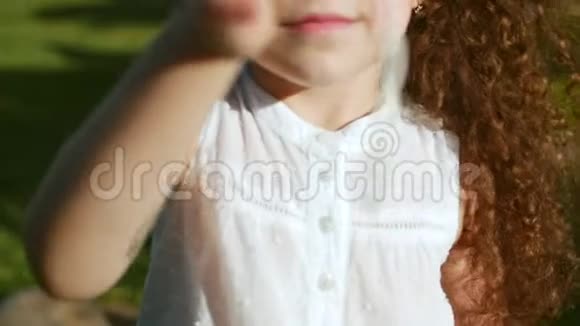 一个快乐可爱的小女孩的特写肖像她留着卷发和红色太阳镜半看着镜头视频的预览图