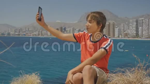 英俊的少年在智能手机上打视频电话展示海上城市天际线背景视频的预览图