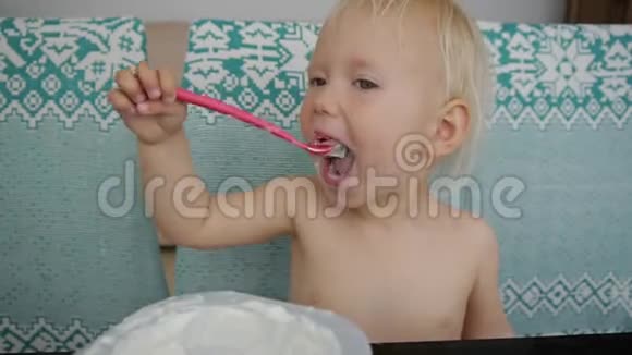 宝宝吃酸奶弄得一团糟笑着的白人蓝眼睛女婴吃酸奶的肖像视频的预览图