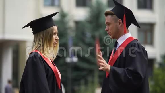 两个在壁炉里的年轻人在毕业典礼前在户外交流视频的预览图