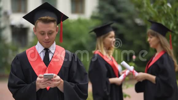 快乐的男性毕业生在智能手机上打字浏览移动应用程序视频的预览图